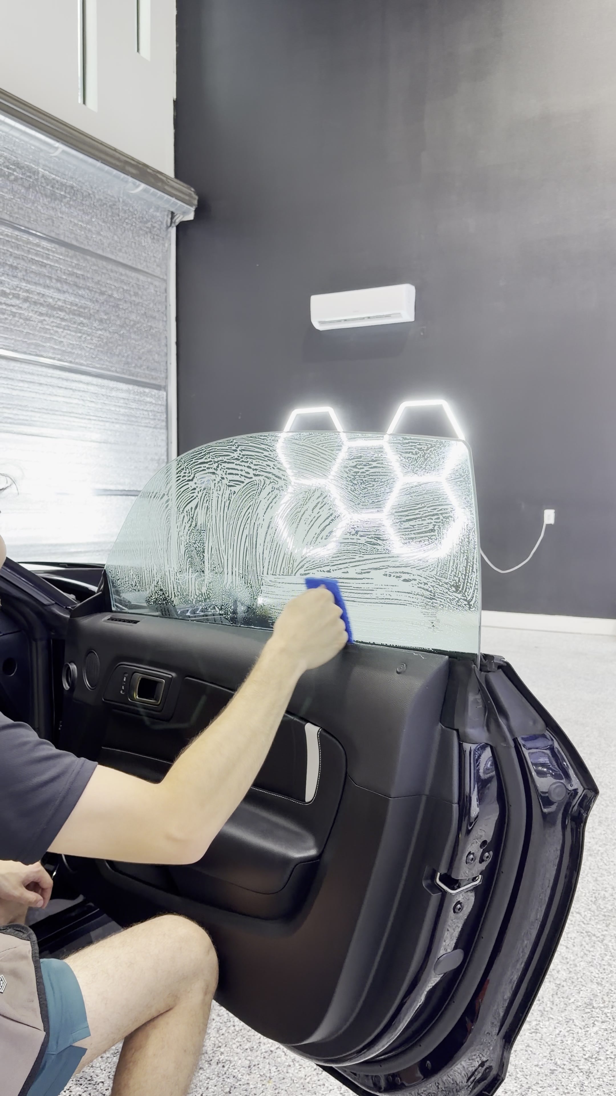 Technician smoothing film onto a vehicle door window