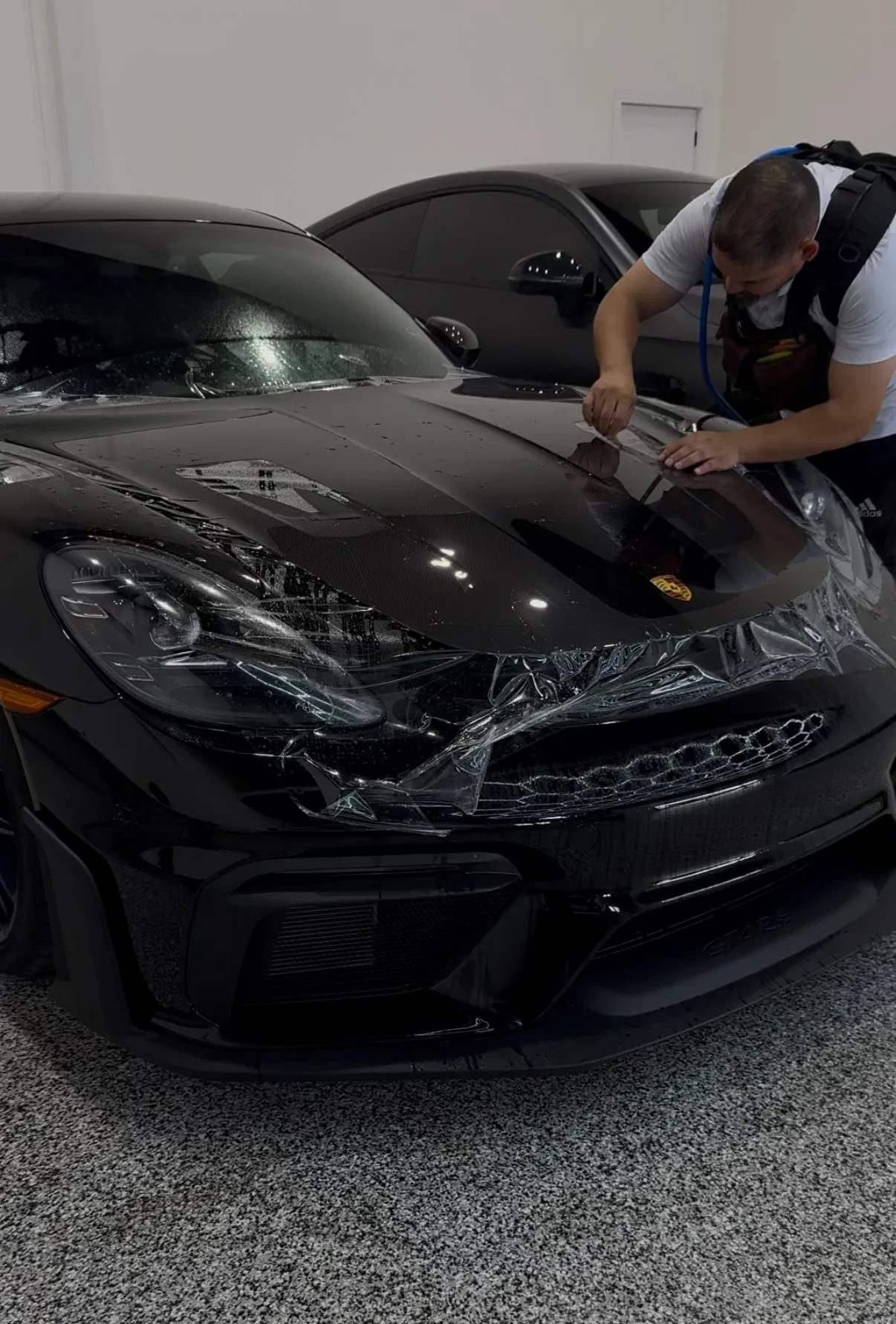 Paint protection film being installed across the front of a black Porsche at Huracán Nero