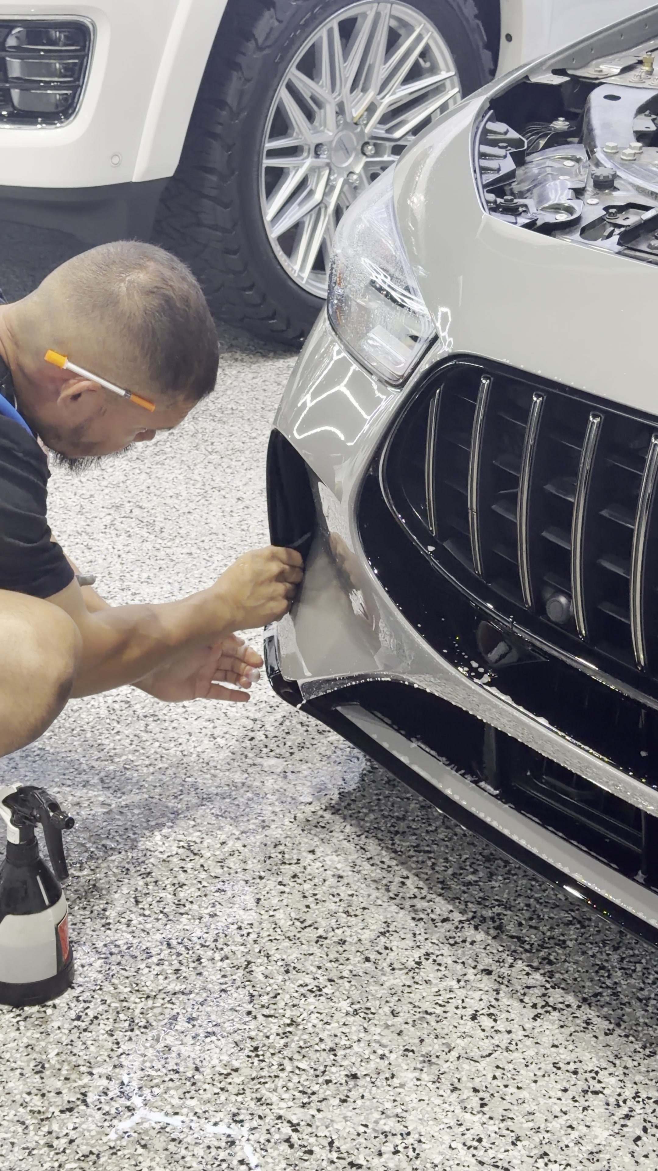 Technician applying PPF to a Mercedes bumper
