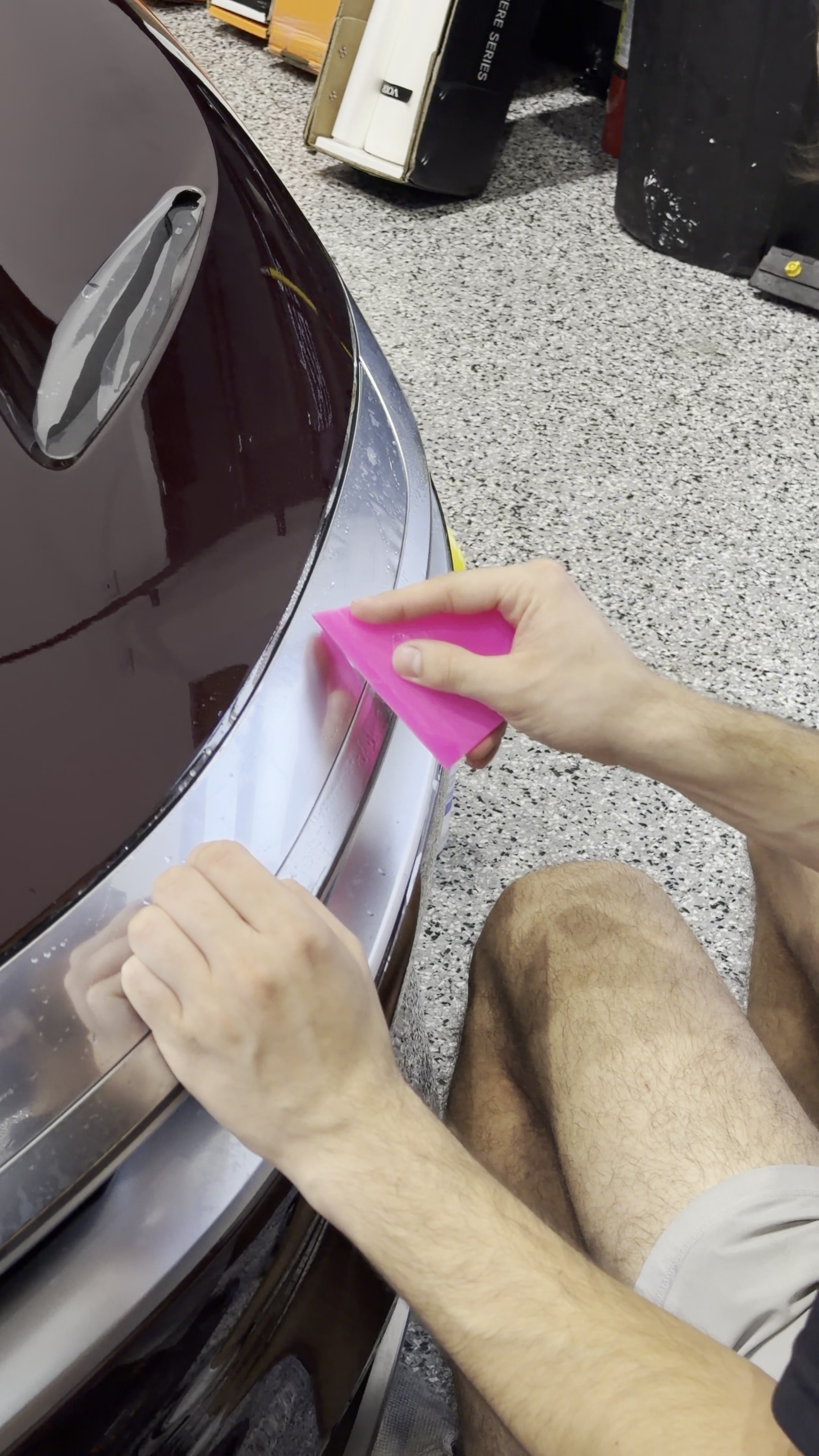 Technician working paint protection film around a bumper edge