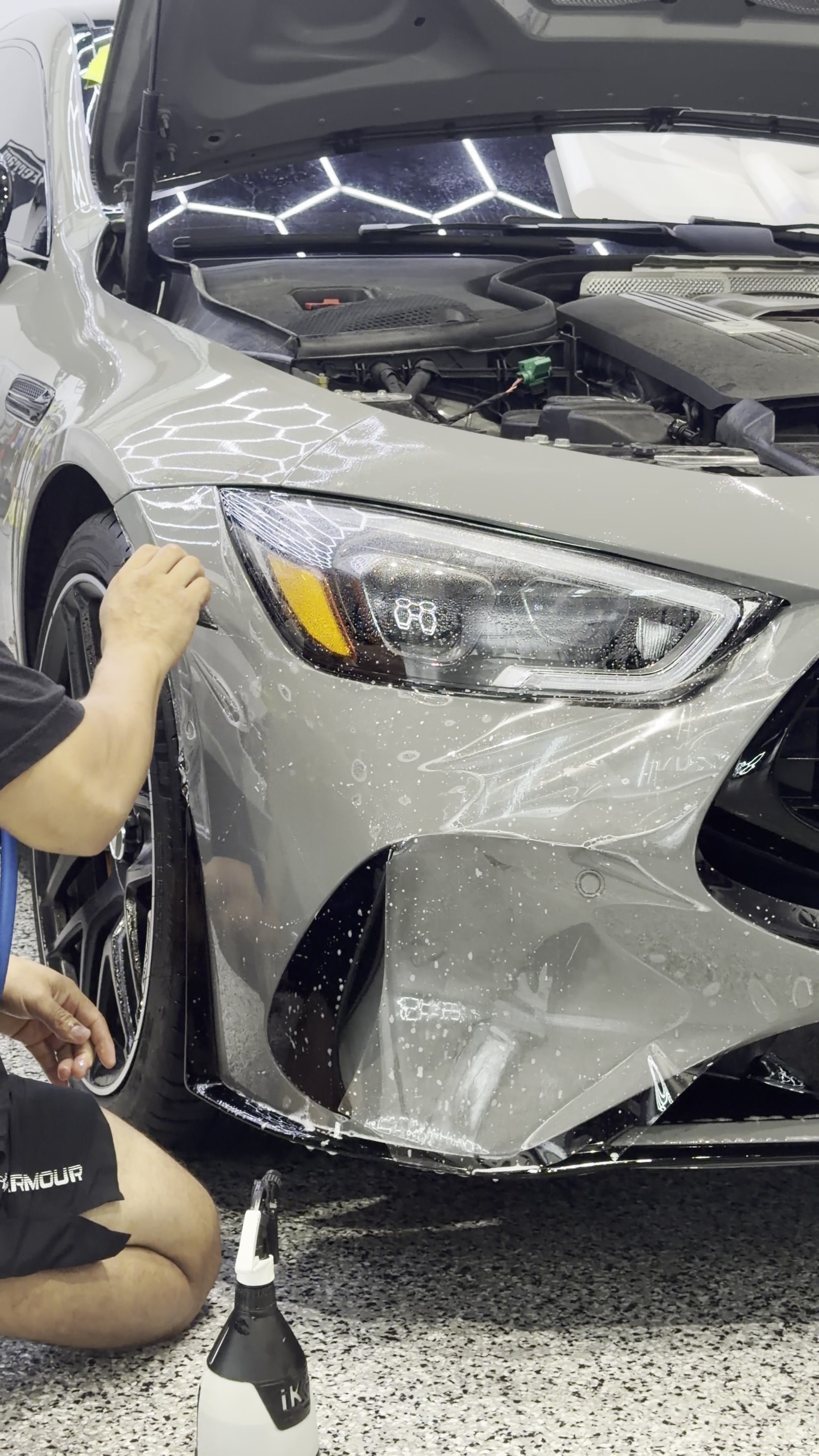 Clear paint protection film being positioned on a silver front bumper