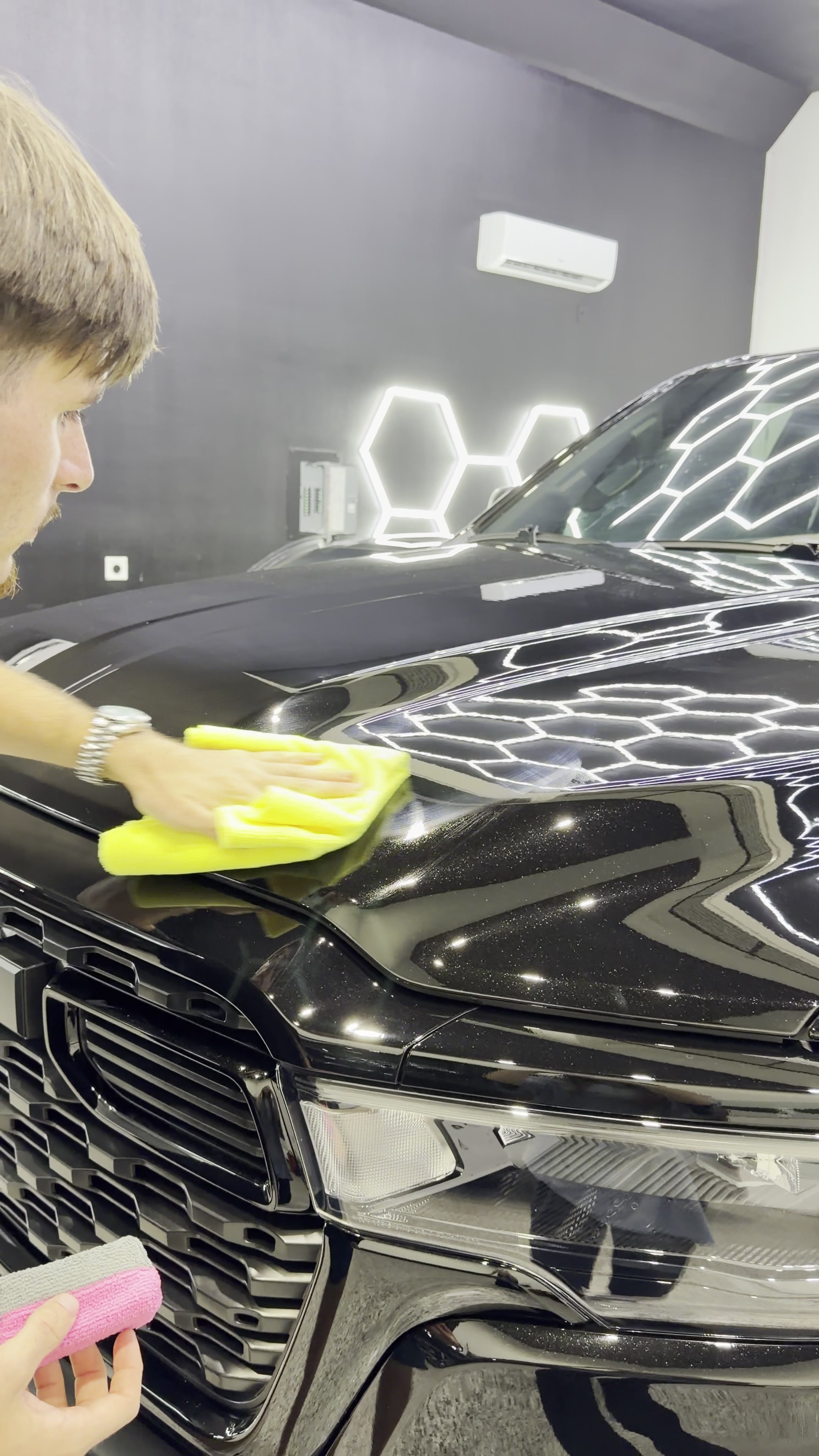 Technician leveling ceramic coating on a front fender