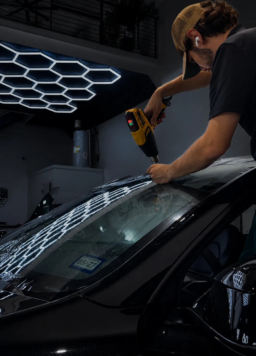 Close-up of a Huracán Nero technician smoothing window film onto glass
